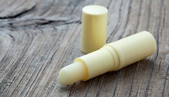 A tube of lip balm lying on a table with the cap off