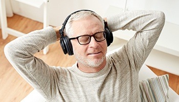 A middle-aged gentleman sitting back with his eyes closed wearing noise-canceling Bluetooth headphones