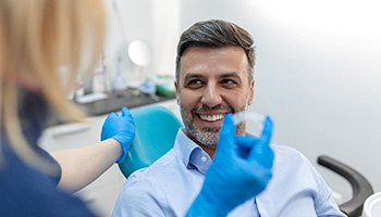 A dentist showing an Invisalign aligner to one of her patients