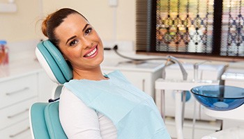 Woman sitting back in dental chair and smiling