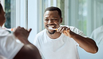 Man in white shirt brushing his teeth
