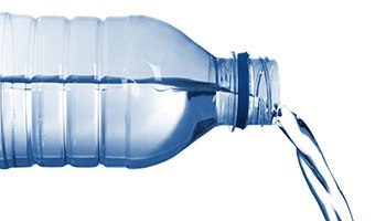 A bottle of water with the cap off and it is pouring out