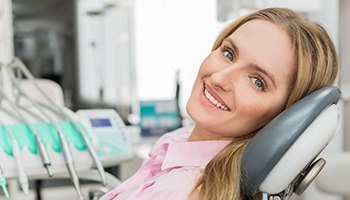 A young woman sitting back in the dentist’s chair and smiling before her visit