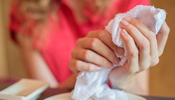 An up-close image of a woman holding a hot towel in her hands