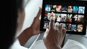 An individual scrolling through Netflix to find a TV show on an iPad