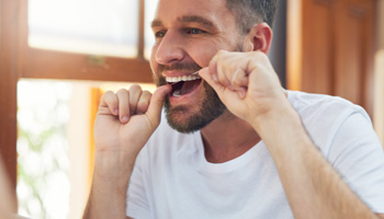 Man flossing his teeth in bathroom