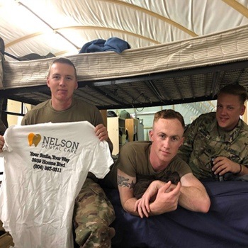 Soldiers overseas holding Nelson Dental Care shirt