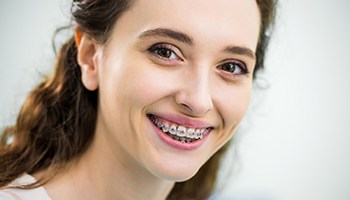 Woman with brown hair smiling with traditional braces