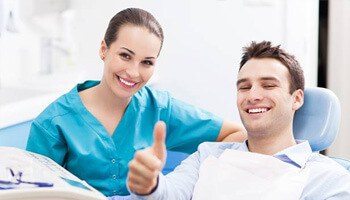 Smiling man in dental chair giving thumbs up