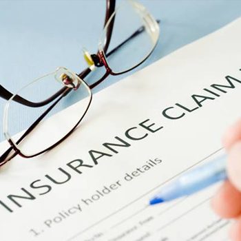 Hand filling out insurance claim form