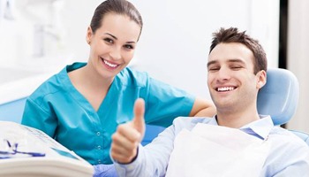 Smiling man in dental chair giving thumbs up