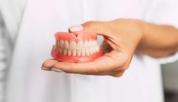 dentist holding a set of full dentures 