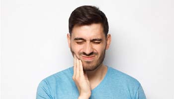Man with tooth pain in need of tooth extraction in Metairie, LA