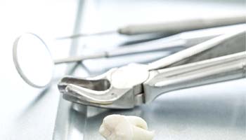 Forceps and extracted tooth on dental tray