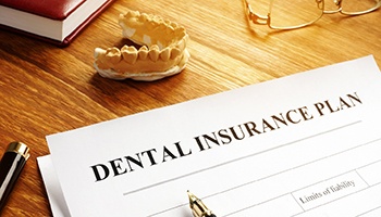 Dental insurance form on table with model of teeth