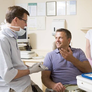 Man in dental chair talking to dentist