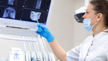 a dentist pointing to a monitor