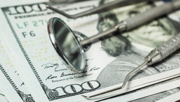 dental instruments sitting atop money 