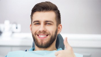 Smiling young man giving a thumbs-up after completing Invisalign in Metairie 