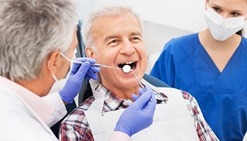 Dentist rubbing swab on elderly patient's teeth