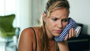 Woman in pain with ice pack on face