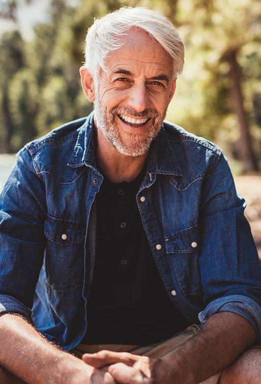 Elderly gentleman in denim jacket flashing a confident smile