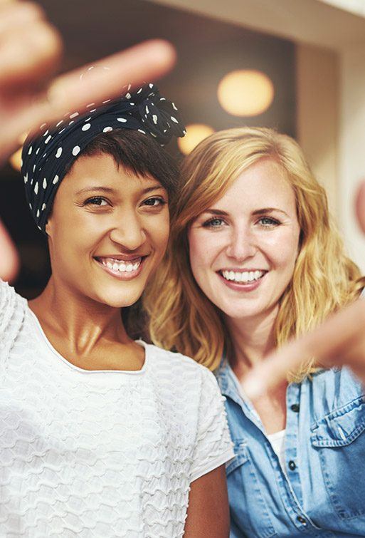 Two ladies framing their gorgeous smiles with hands