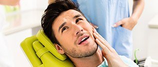 Concerned man holding cheek during dental examination