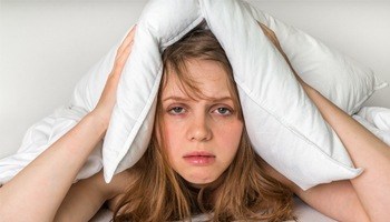 A woman tired with a pillow over her head