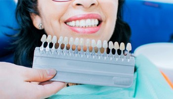 a dentist matching the shade of a patient’s teeth