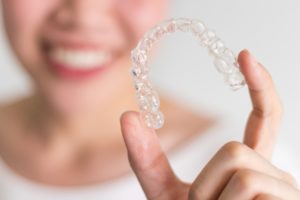 Woman holding aligner showing the benefits of Invisalign. 