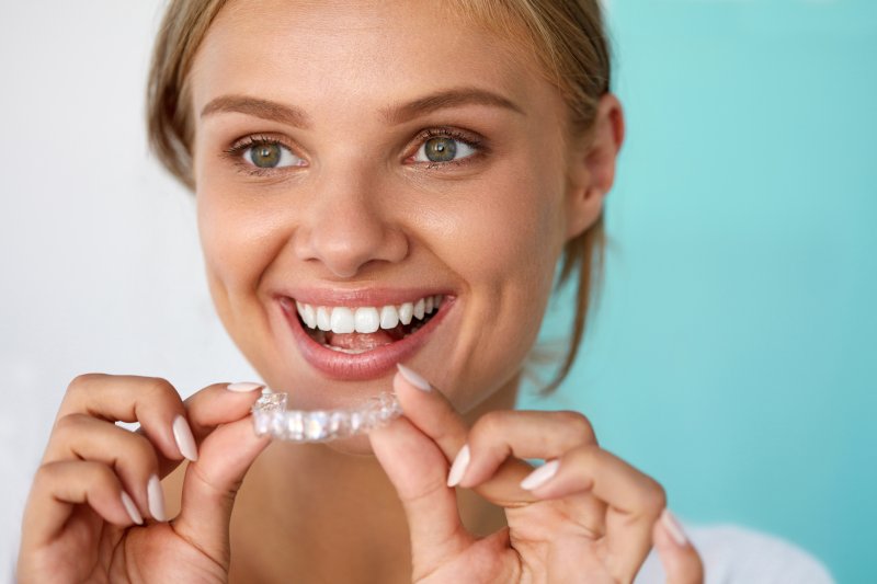 A woman smiling as she prepares to use her store-bought teeth whitening kit