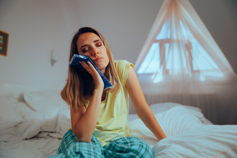 Patient holding cold compress on jaw due to dental emergency
